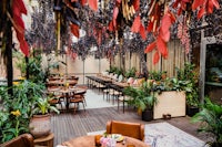 an outdoor dining area with plants hanging from the ceiling